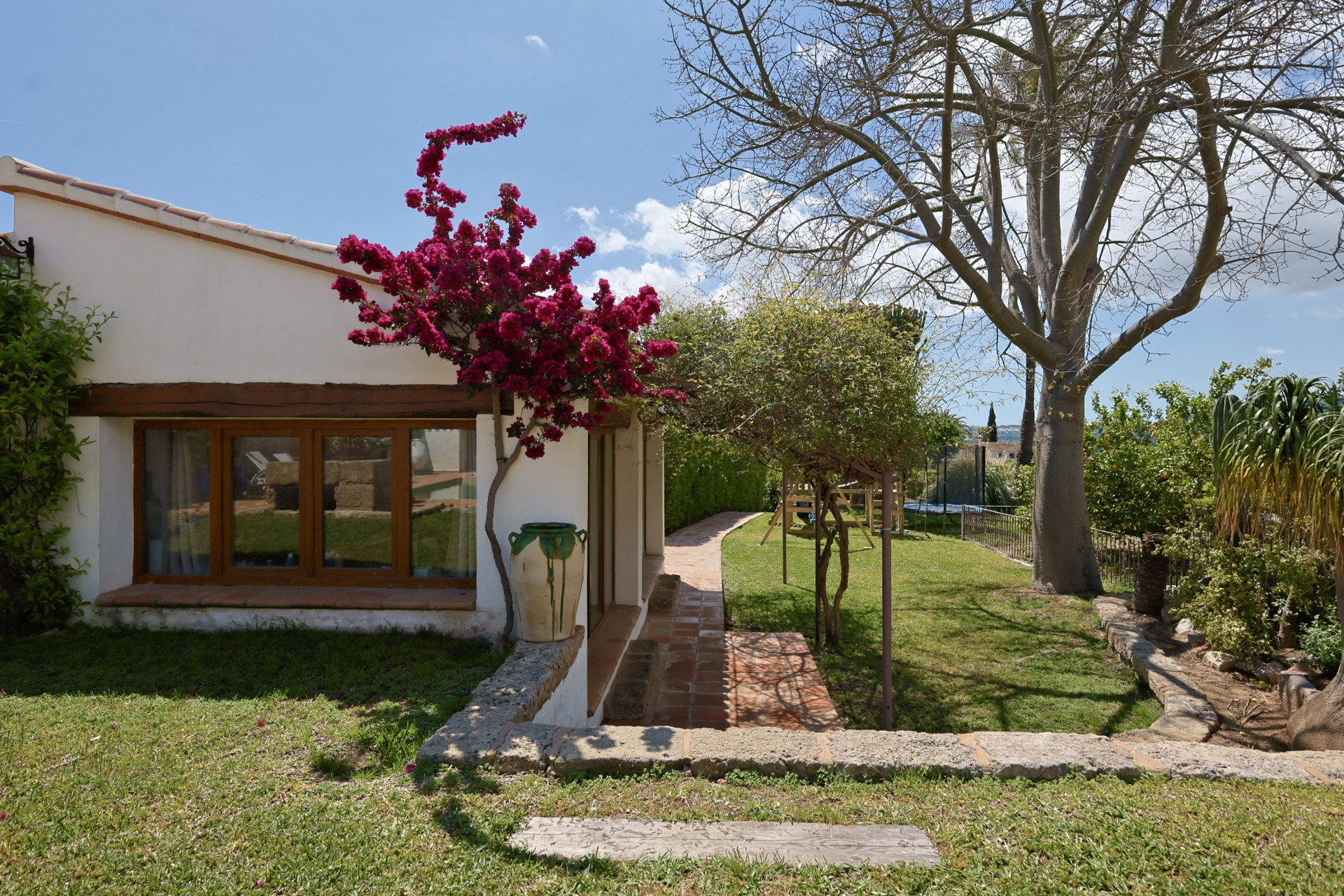 Vue du jardin avec bougainvillier fuchsia grimpant sur la façade de la villa à Jávea. Fenêtre avec cadre en bois.