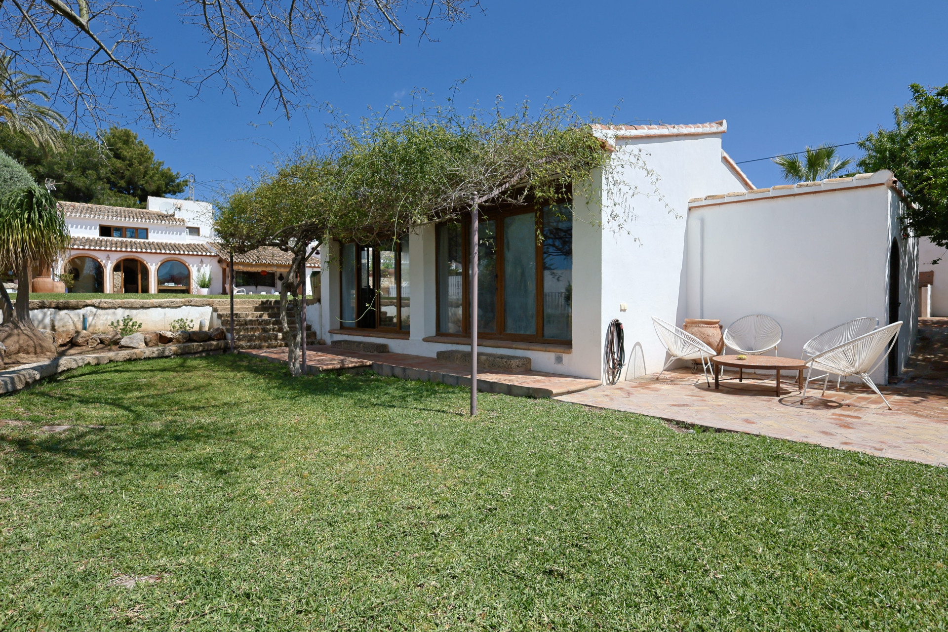 Vue sur le jardin et terrasse avec mobilier d'extérieur dans villa à Jávea.