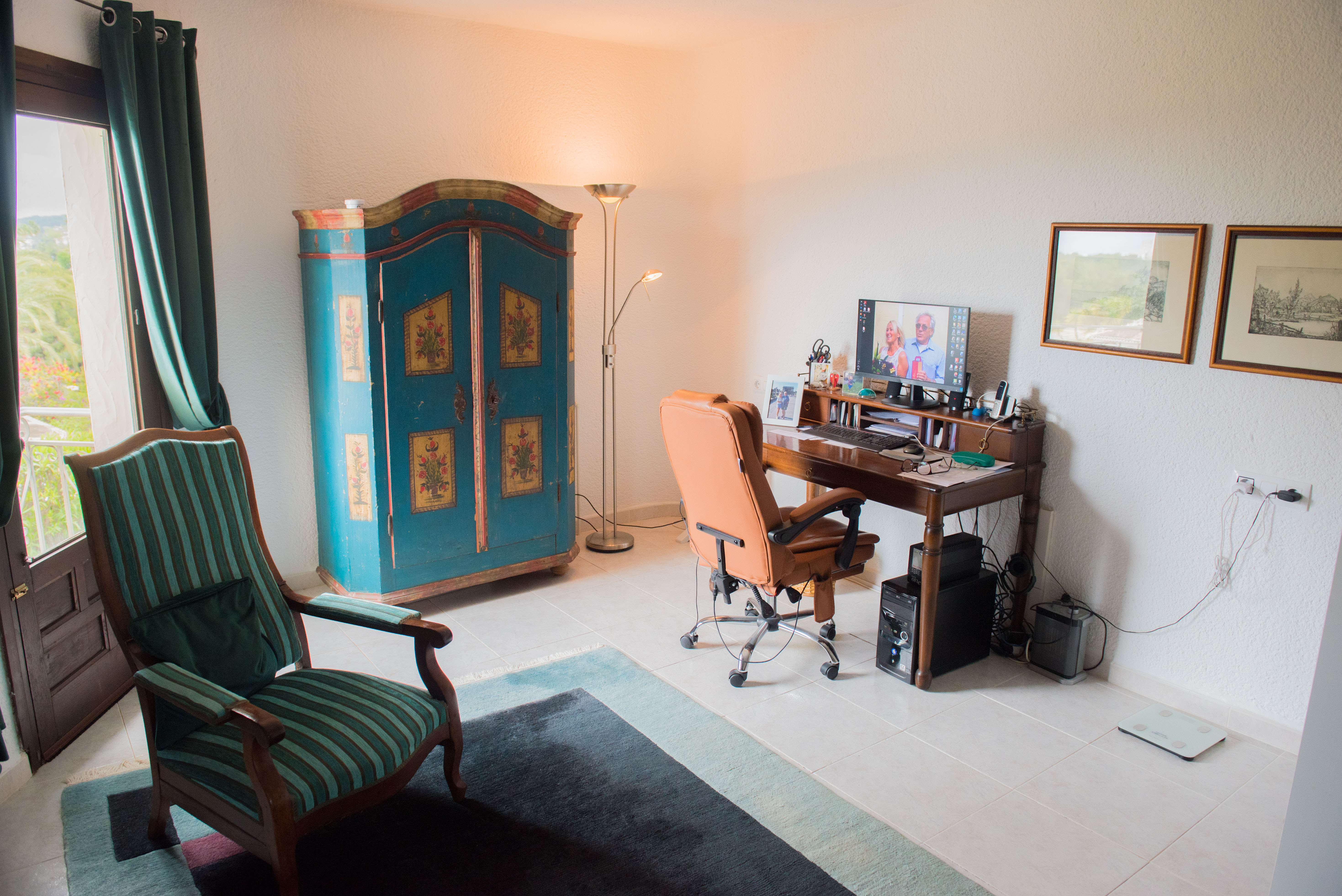 Bureau fonctionnel avec secrétaire en bois classique, armoire rustique décorée et fauteuil en cuir. Profite d'une lumière naturelle et d'un accès terrasse.