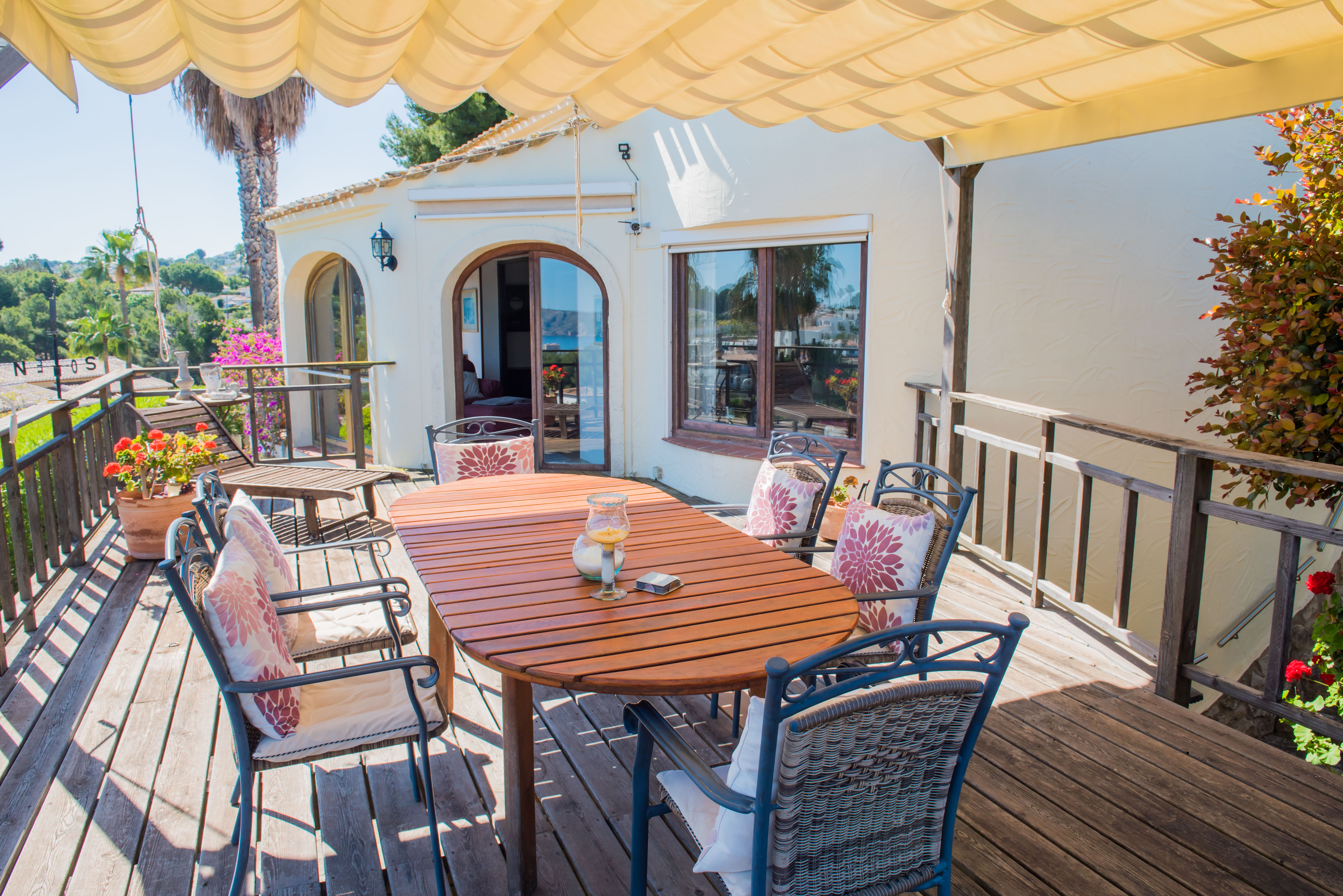 Terrasse couverte avec table en bois et chaises rembourrées, idéale pour profiter des vues panoramiques sur la mer Méditerranée.