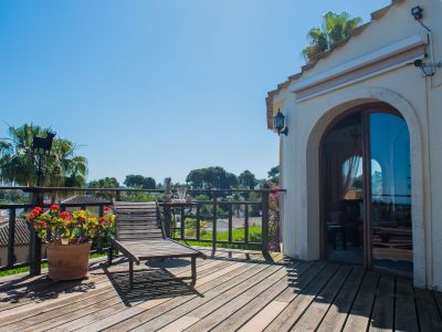 Terrasse ensoleillée avec plancher en bois, chaise longue et vue sur le paysage méditerranéen.