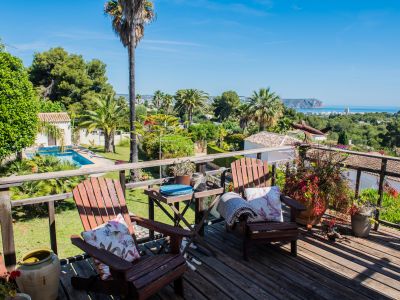 Vue depuis la terrasse en bois avec chaises Adirondack, jardins et vue panoramique sur la mer à Jávea.