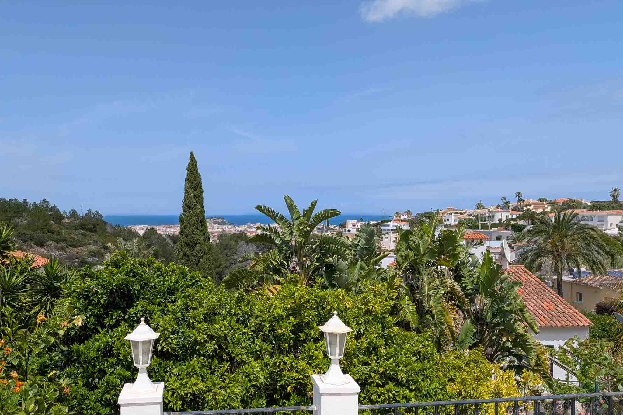 Vue panoramique sur la mer et Dénia depuis la terrasse supérieure, entourée d'une végétation méditerranéenne et de citronniers.