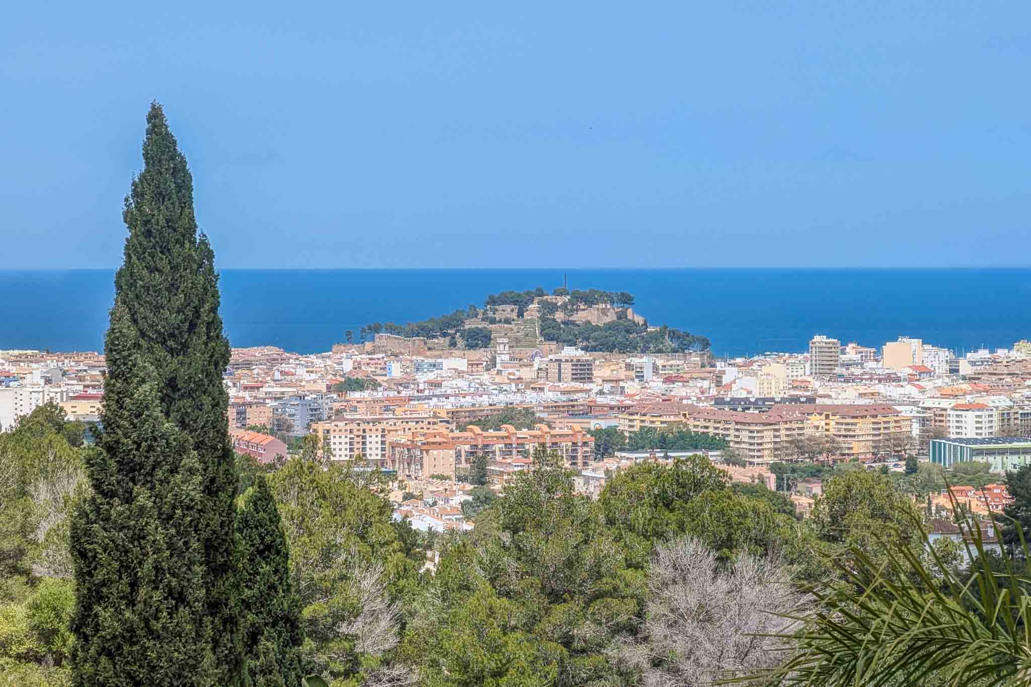 Vues panoramiques depuis la propriété sur le château de Dénia et la mer Méditerranée, encadrées par la végétation locale et des cyprès.