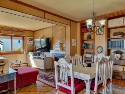 Salle à manger avec étagères en bois et table rustique blanche avec coussins rouges.