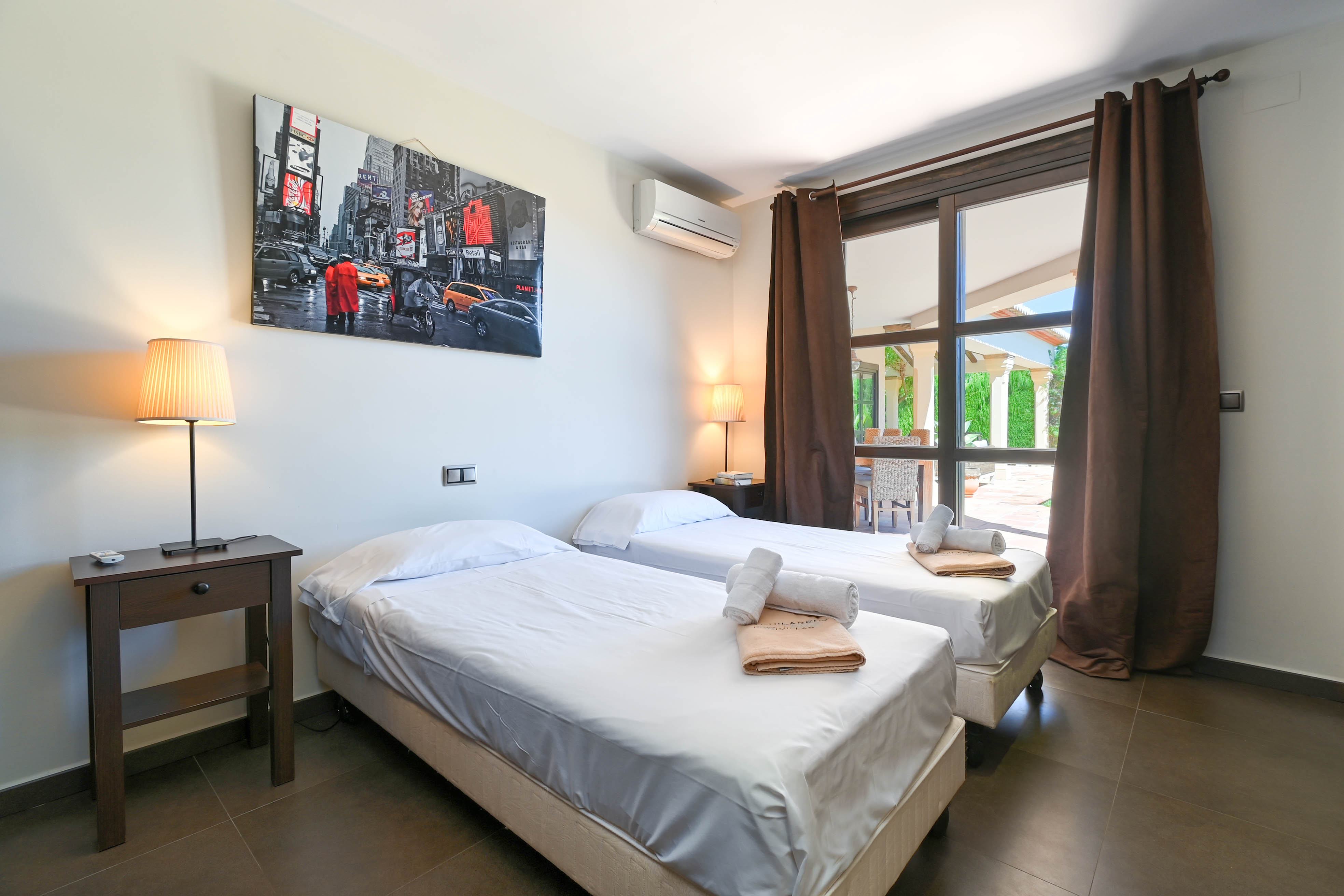 Chambre avec lits jumeaux, linge blanc et vue sur l'extérieur.