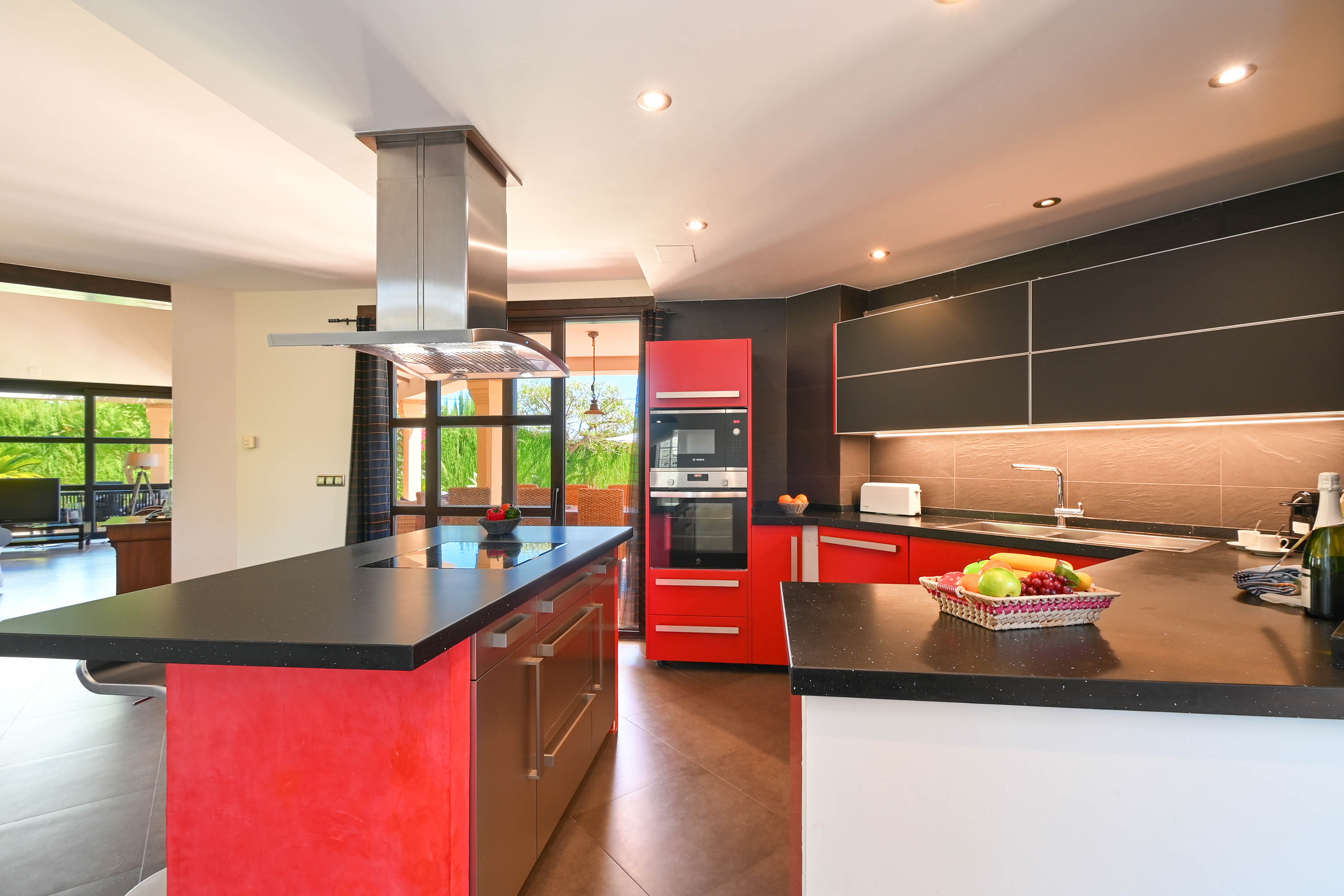 Cuisine moderne avec comptoirs en granit noir, armoires rouges et noires et appareils électroménagers en acier inoxydable.