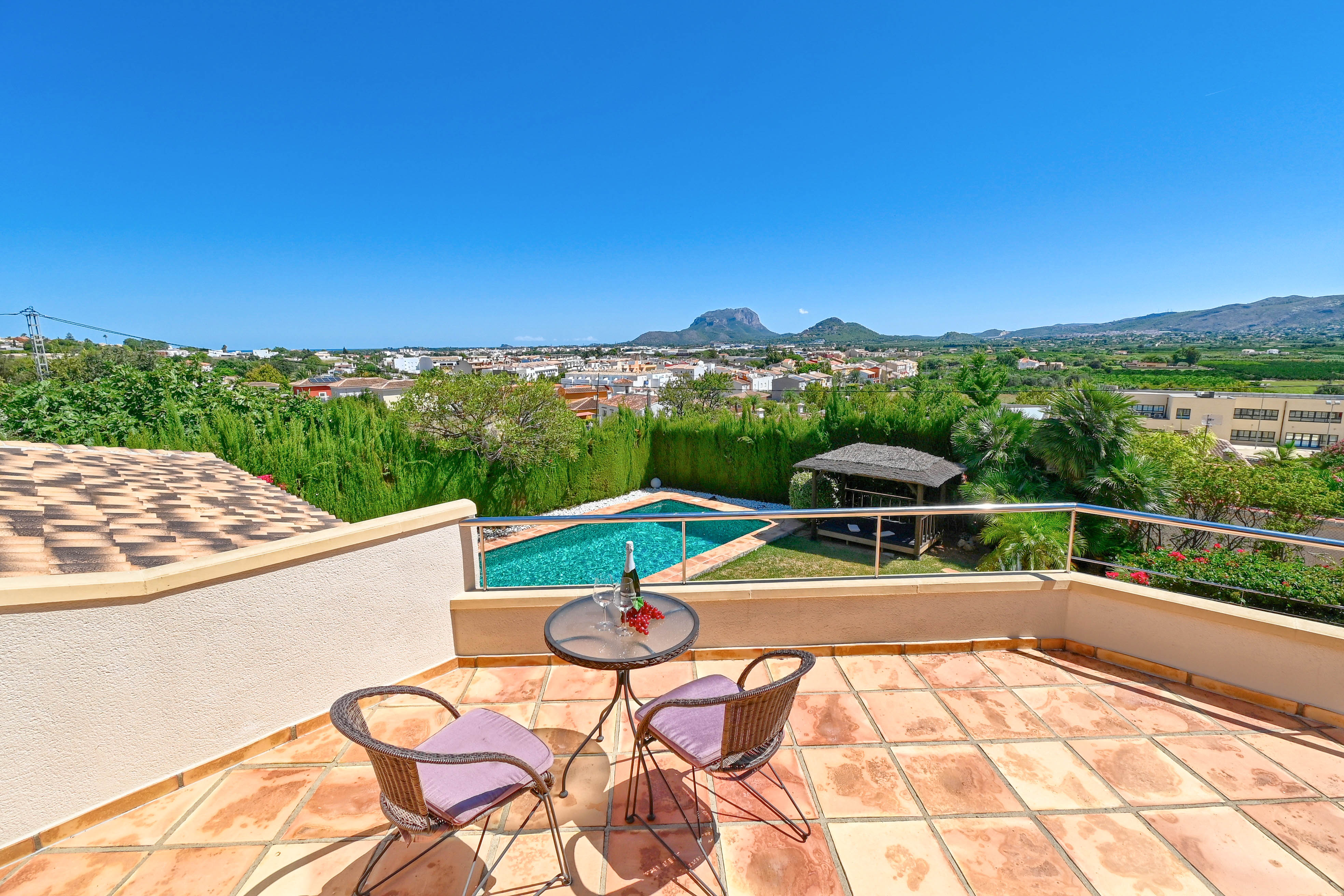 Terrasse avec table de bistro, donnant sur la piscine et le paysage montagneux de Denia.