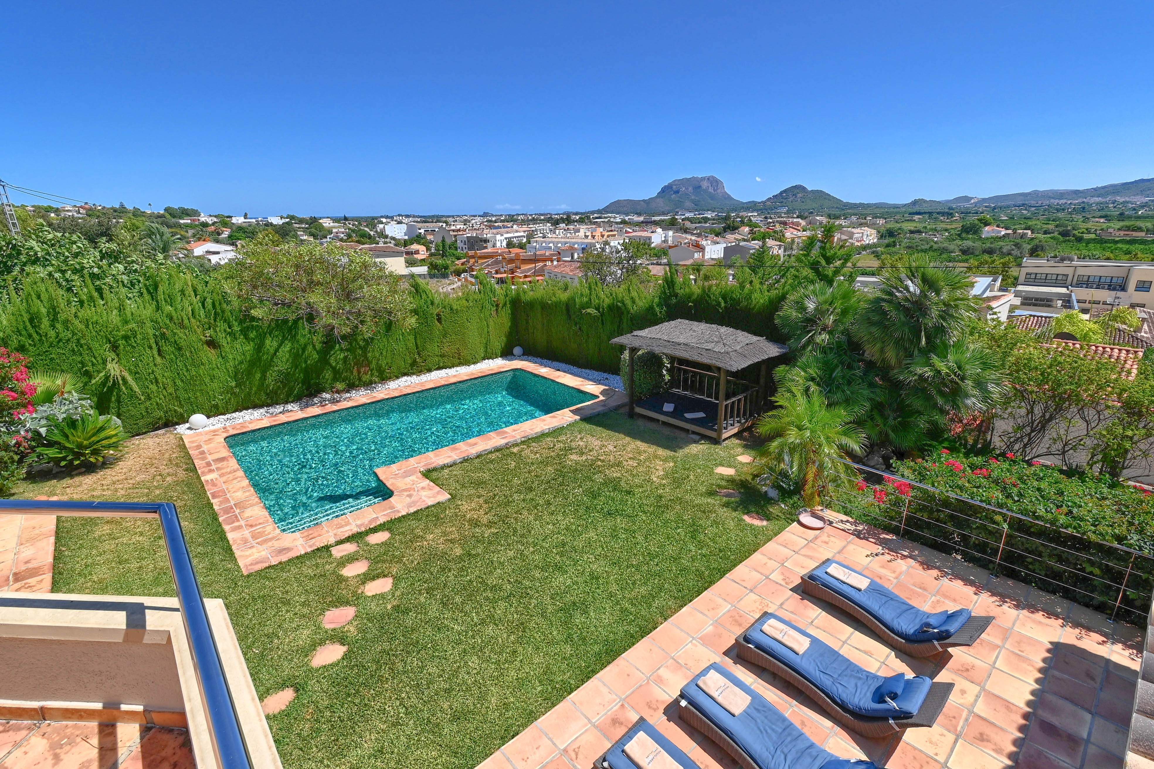 Vue surélevée du jardin avec piscine turquoise et gazebo au toit de chaume.