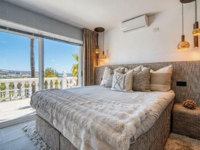 Chambre lumineuse avec accès terrasse et vue mer. Lit avec tête de lit rembourrée et linge de lit aux tons neutres.