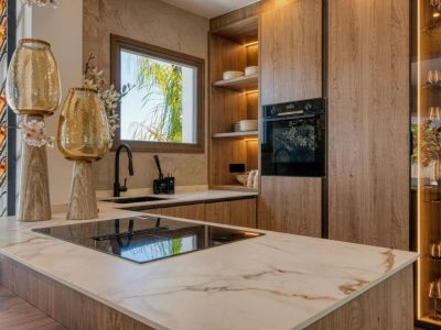 Détail de la cuisine avec îlot en marbre veiné, armoires en bois clair et électroménagers modernes.