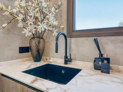 Détail du comptoir avec évier noir, robinet moderne et décoration florale. Élégance et fonctionnalité dans la cuisine.