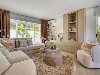 Salon lumineux avec canapé modulable, tapis rond à poils longs et meuble de rangement intégré.