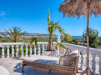 Terrasse ensoleillée avec lit de repos en rotin et vue panoramique sur Jávea.