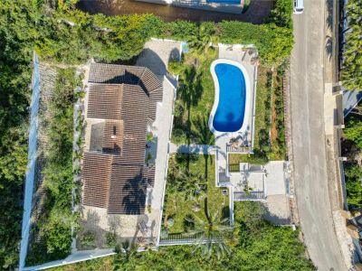 Vue aérienne de la villa avec piscine bleu vif, entourée de jardins et d'une végétation luxuriante à Jávea.