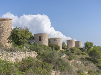 Vue sur les moulins à vent historiques en pierre de Jávea, intégrés dans le paysage méditerranéen.
