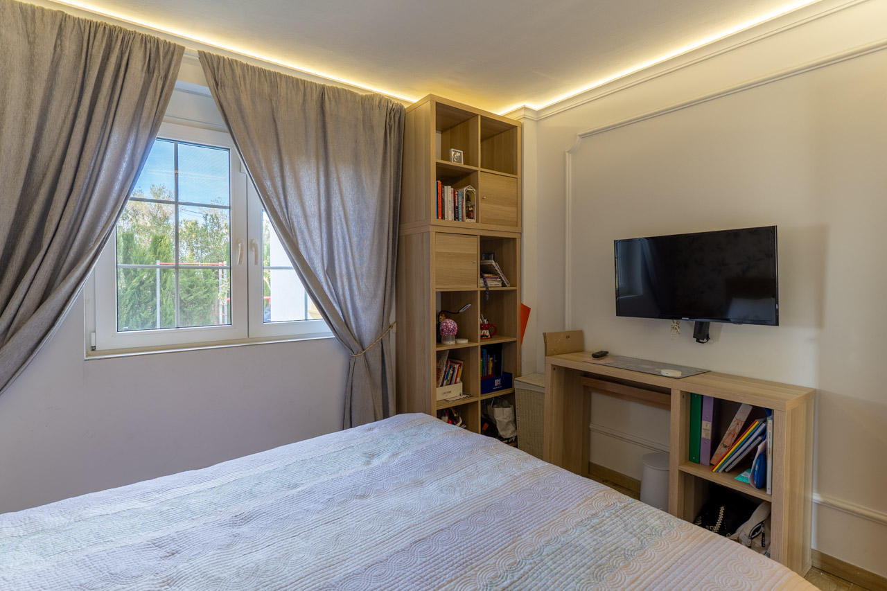 Chambre lumineuse avec étagères en bois clair et rideaux gris près de la fenêtre.