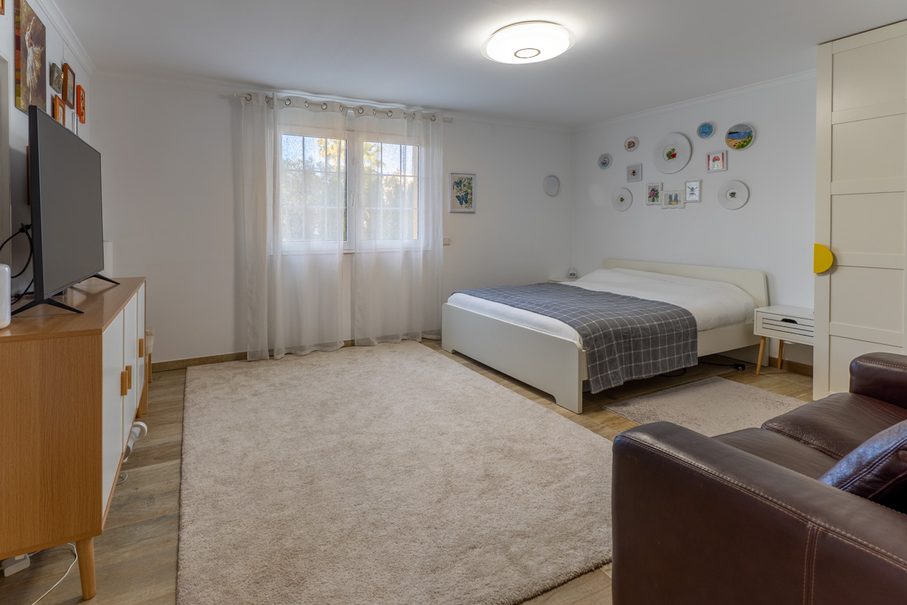 Chambre lumineuse avec lit blanc, tapis moelleux et décorations murales.