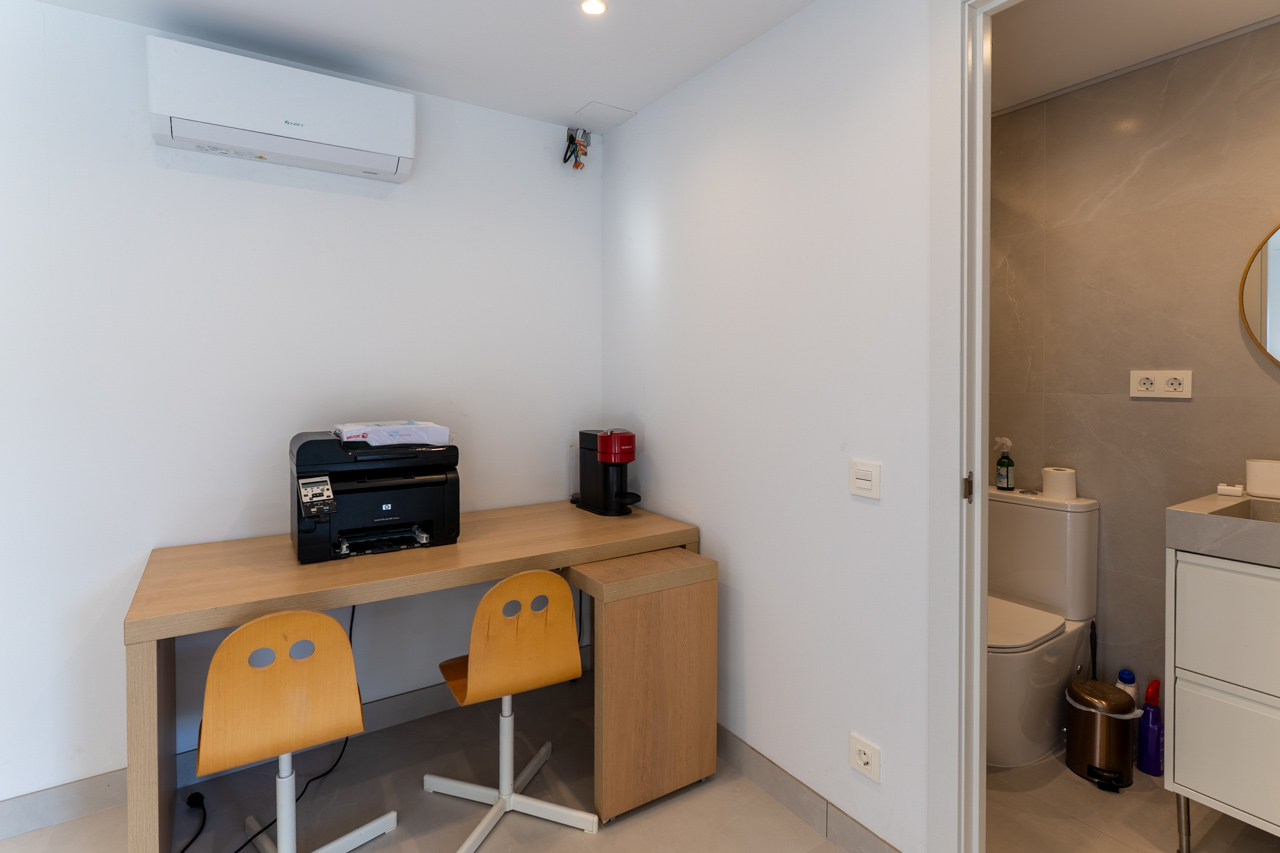 Coin bureau fonctionnel avec bureau en bois clair et accès à une salle de bain attenante.