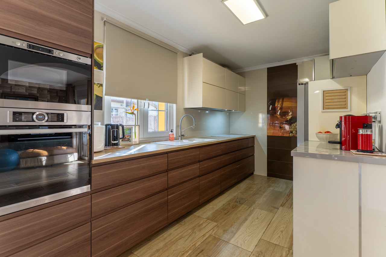 Cuisine moderne avec armoires en bois, comptoir clair et carrelage imitation bois.