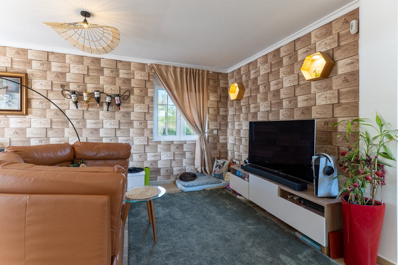 Salon avec papier peint à motifs de caisses de vin et canapé en cuir marron.