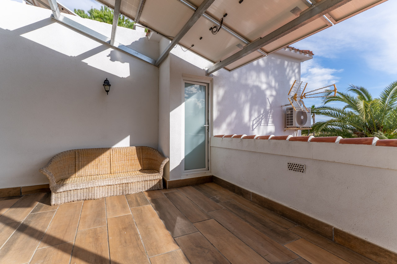 Terrasse couverte avec sol en céramique et canapé en osier, éclairée par la lumière naturelle et avec accès à l'extérieur.