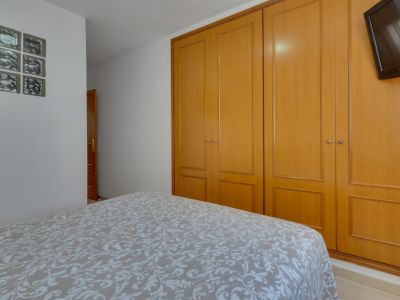 Chambre lumineuse avec lit double et armoire en bois intégrée. Décoration fonctionnelle et minimaliste.