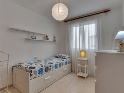 Chambre lumineuse avec lit simple, étagères décoratives et détails nautiques.