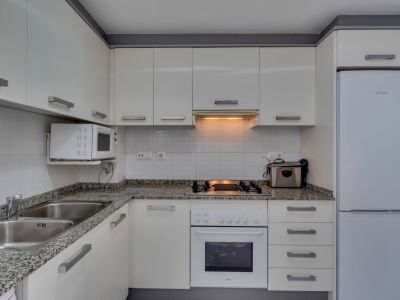 Cuisine fonctionnelle avec plan de travail en granit, électroménager blanc et lumière chaude.
