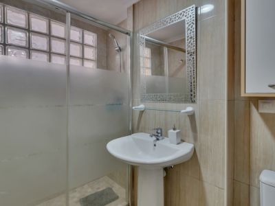 Détail de la salle de bain avec douche en pavés de verre et lavabo sur pied.