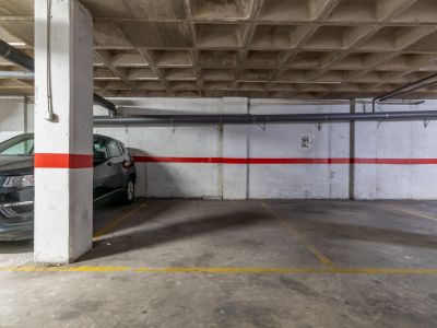 Place de parking souterrain avec sol en béton et plafond à caissons.