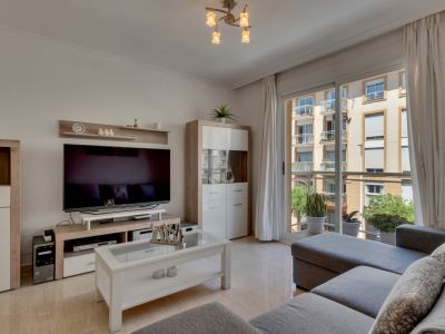 Salon lumineux avec mobilier moderne et accès au balcon avec vue sur la ville.