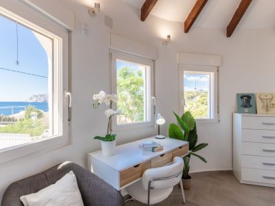 Bureau lumineux avec vue sur la mer, bureau moderne et détails décoratifs.