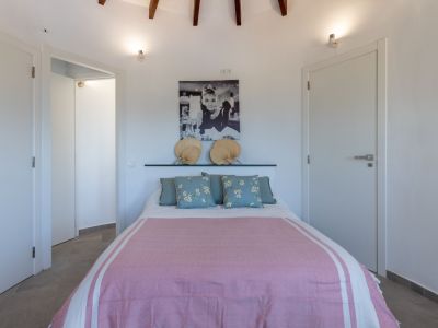 Chambre lumineuse avec lit double, linge de lit rose et tête de lit ornée d'éventails.
