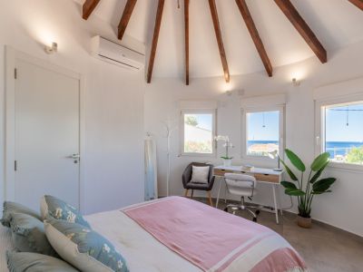 Chambre lumineuse avec plafond voûté à poutres apparentes et bureau avec vue sur la mer.