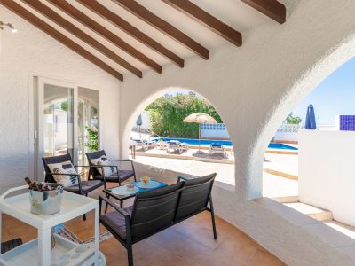 Terrasse couverte avec vue sur la piscine et poutres apparentes.