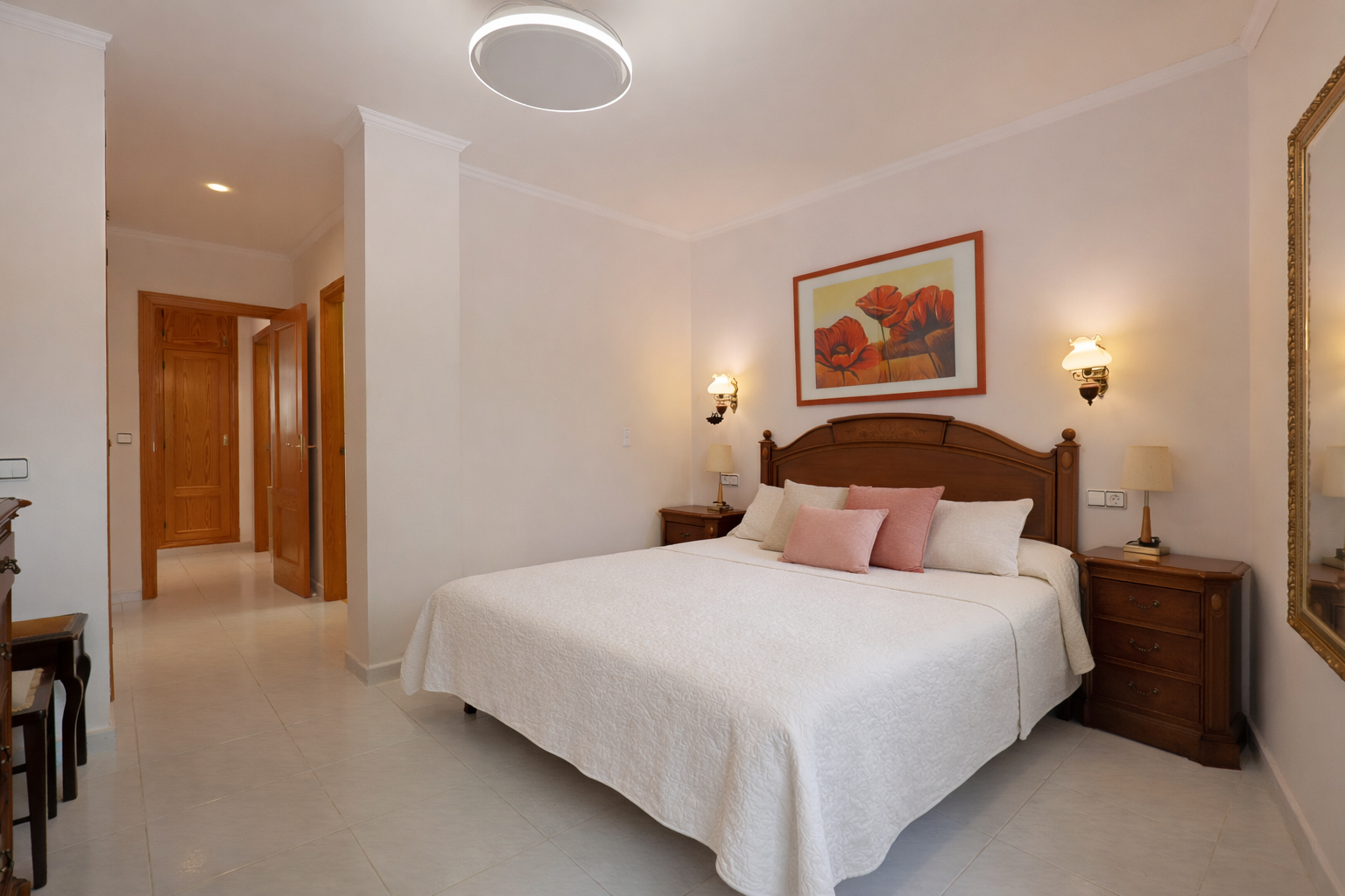 Chambre lumineuse avec lit double, tables de chevet en bois et carrelage.
