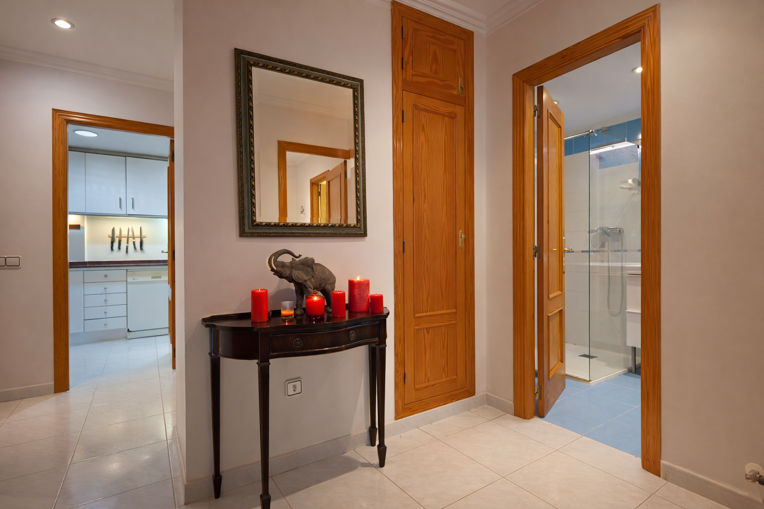Détail du couloir avec console en bois, miroir et accès à la salle de bain.