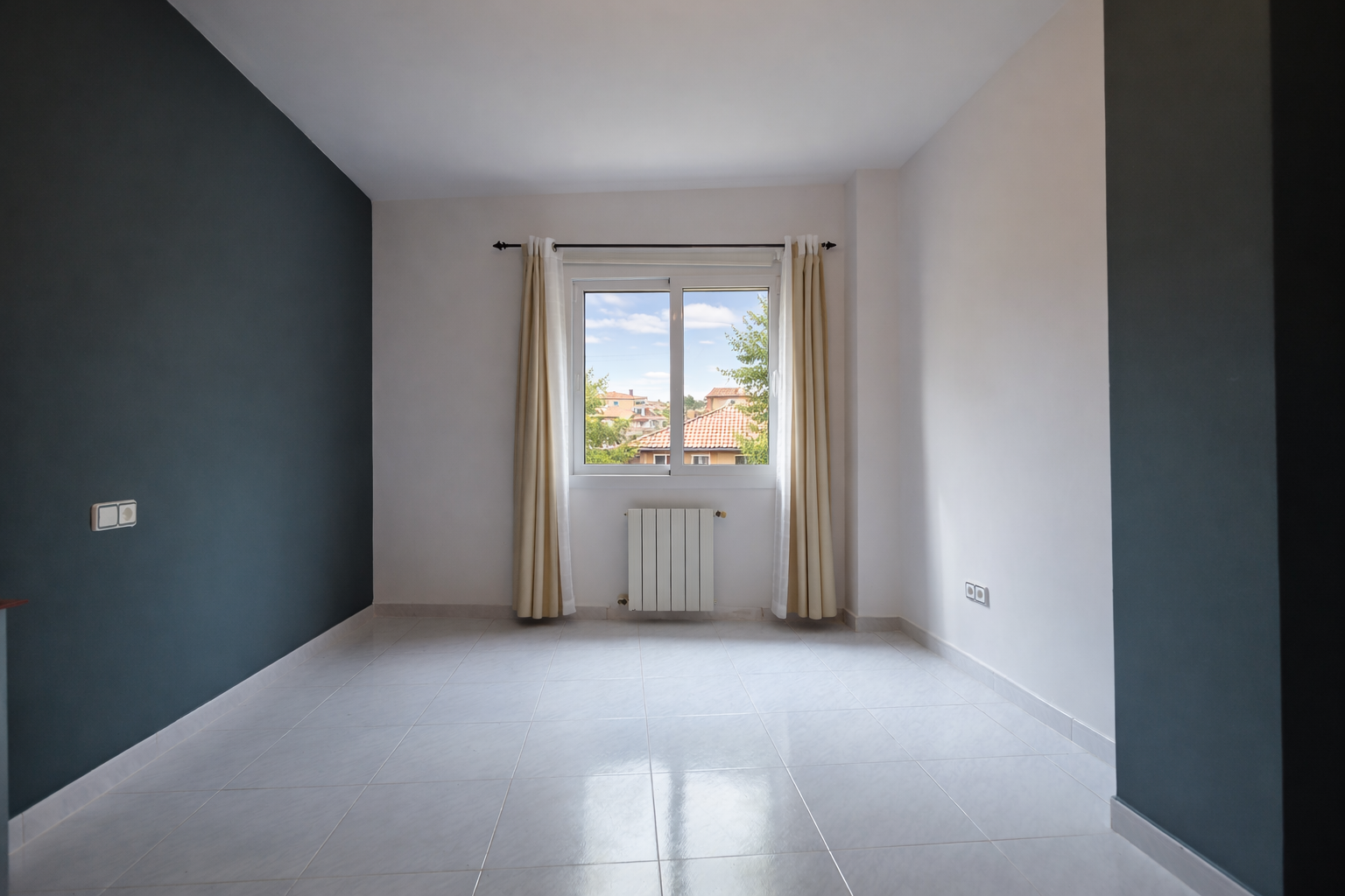 Pièce lumineuse avec mur bleu plomb, fenêtre avec vue et sol carrelé.