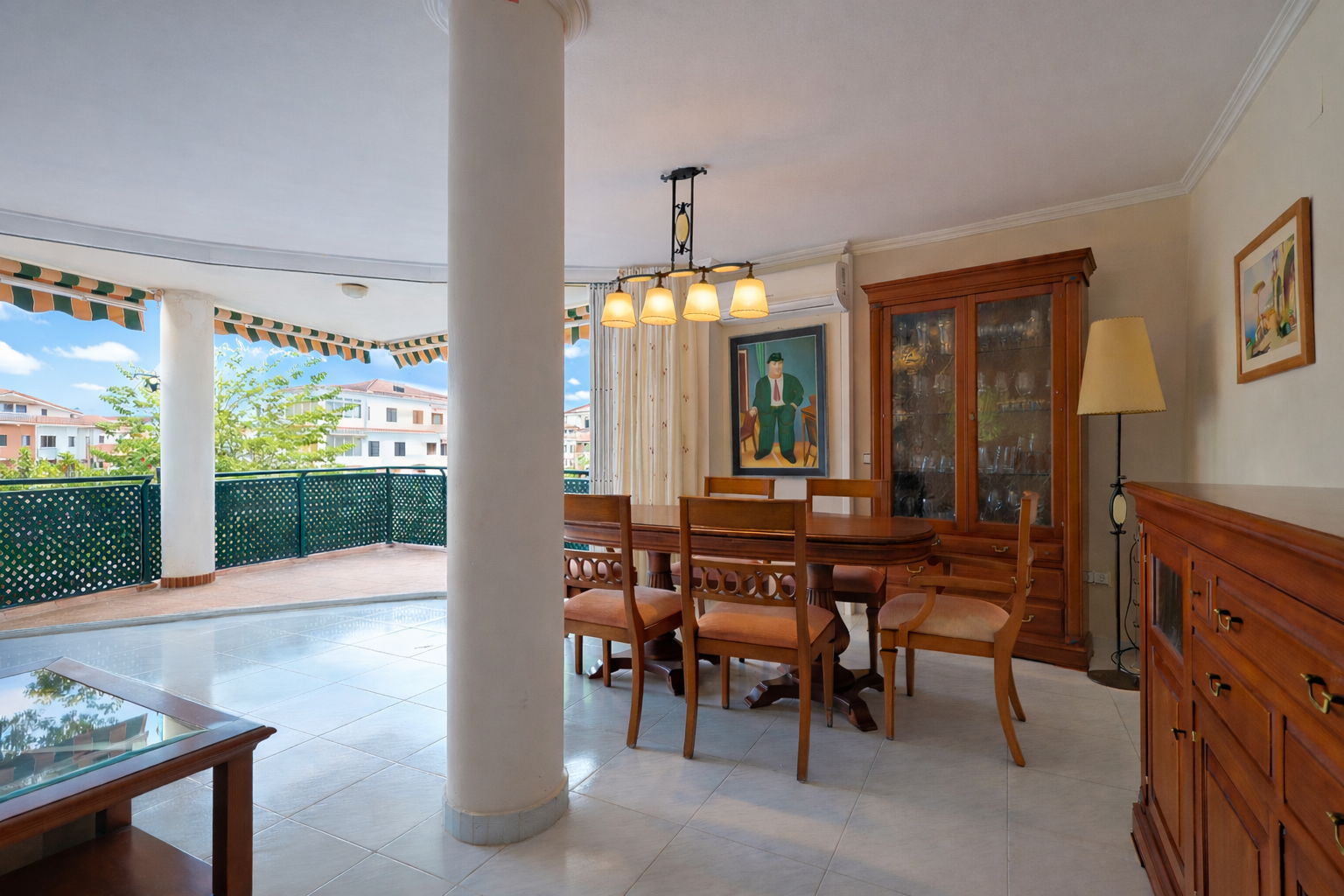 Salle à manger lumineuse avec accès terrasse, mettant en valeur un mobilier en bois classique et un carrelage clair.