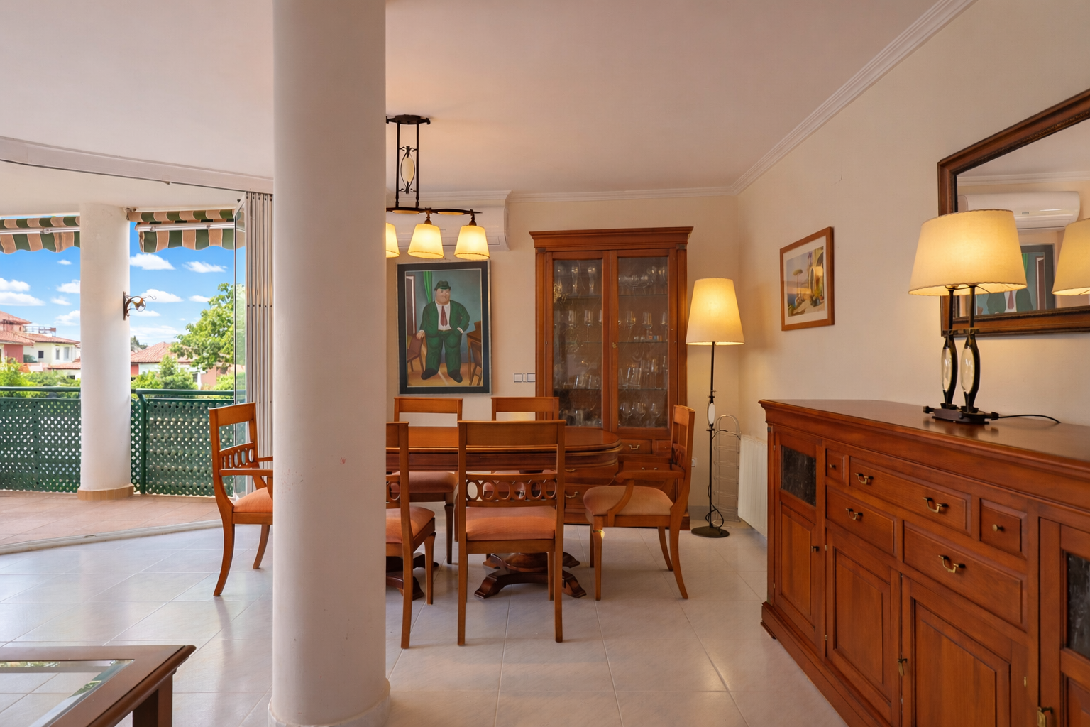 Salle à manger lumineuse avec accès terrasse. Mobilier classique en bois et carrelage en céramique.
