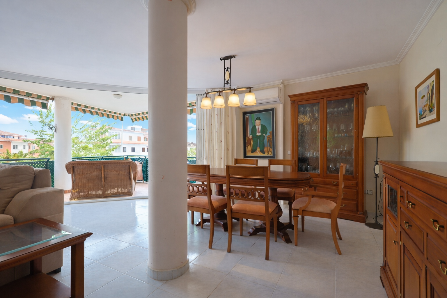 Salle à manger lumineuse avec accès terrasse, table en bois et vitrine classique.