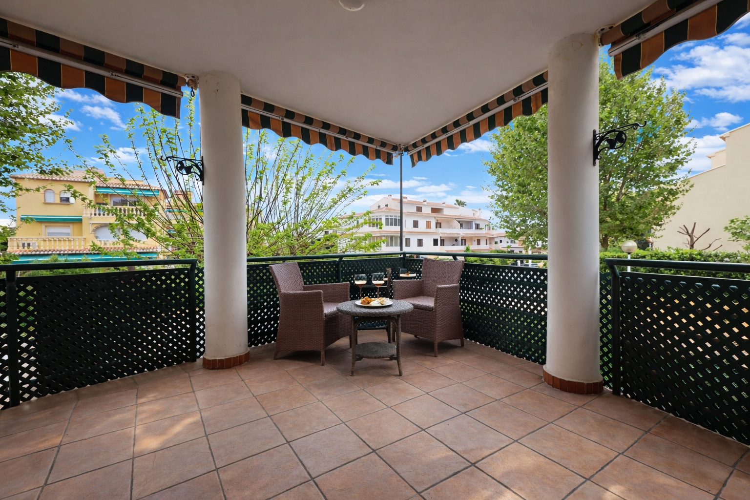 Terrasse couverte avec carrelage et vue sur les immeubles résidentiels.