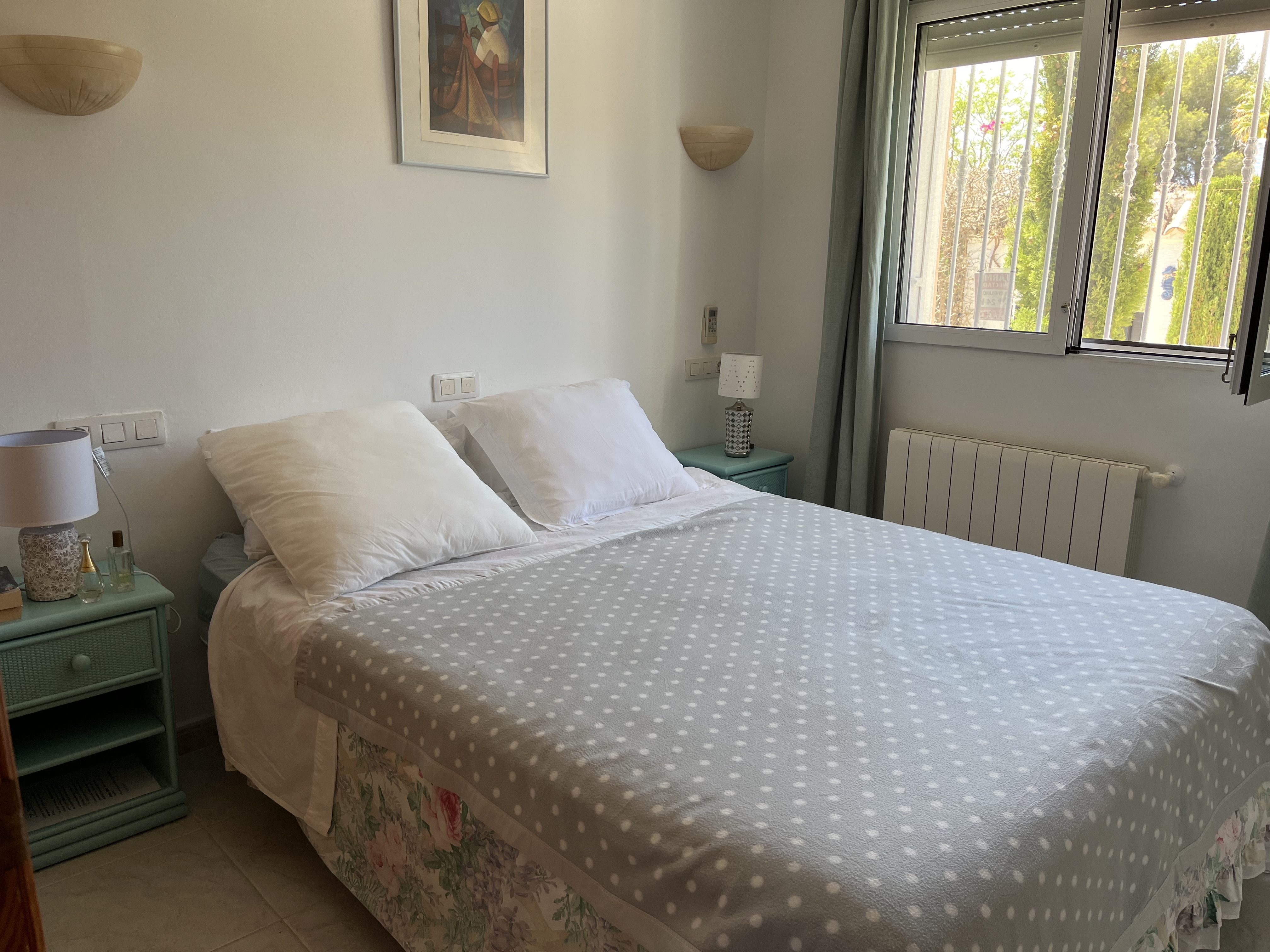 Chambre lumineuse avec lit double, table de chevet turquoise et détails décoratifs.