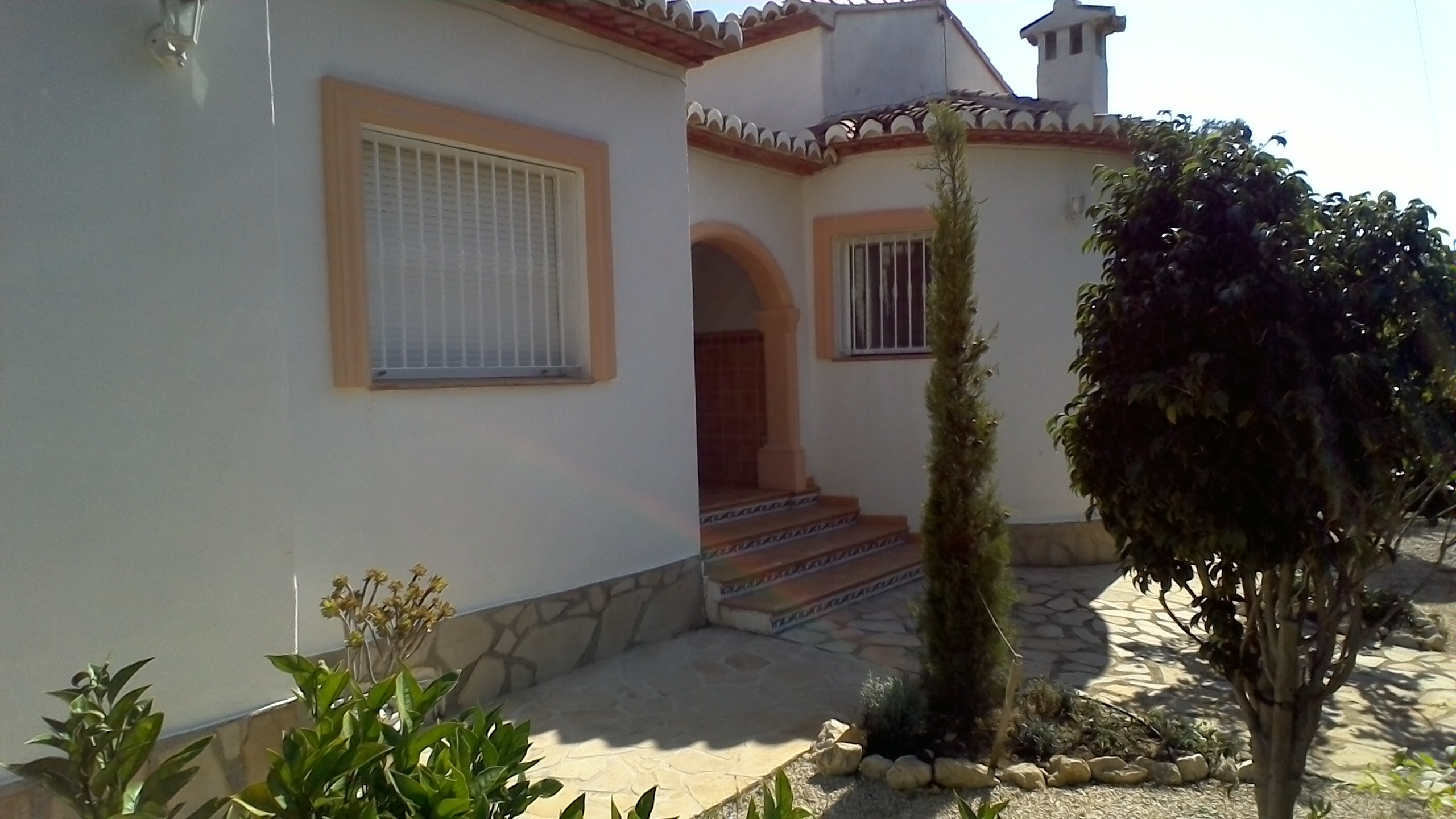 Façade de villa avec détails en pierre et accès en escalier avec carreaux décoratifs.