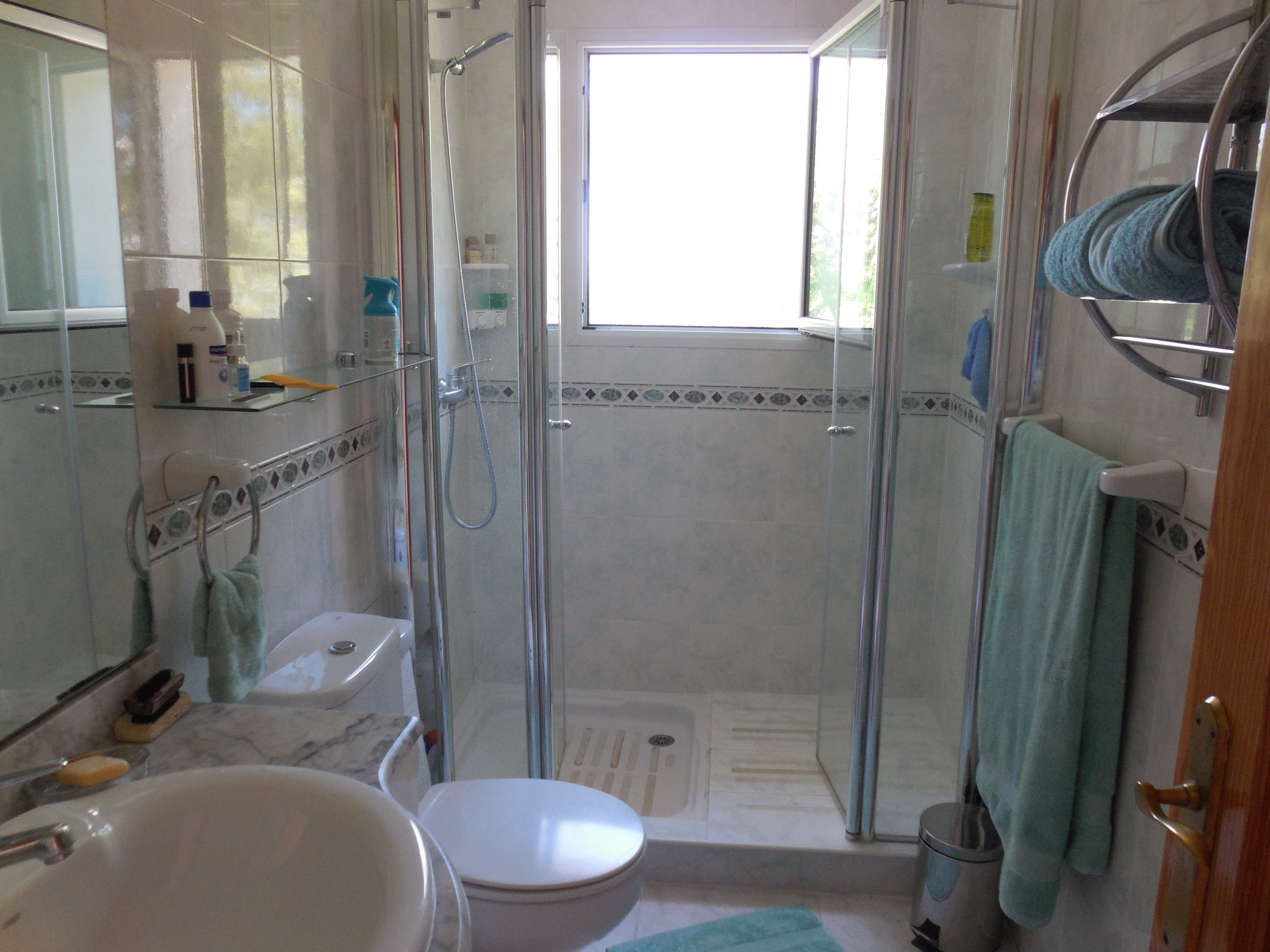 Salle de bain avec douche en verre, lavabo en marbre et accents de carreaux décoratifs.