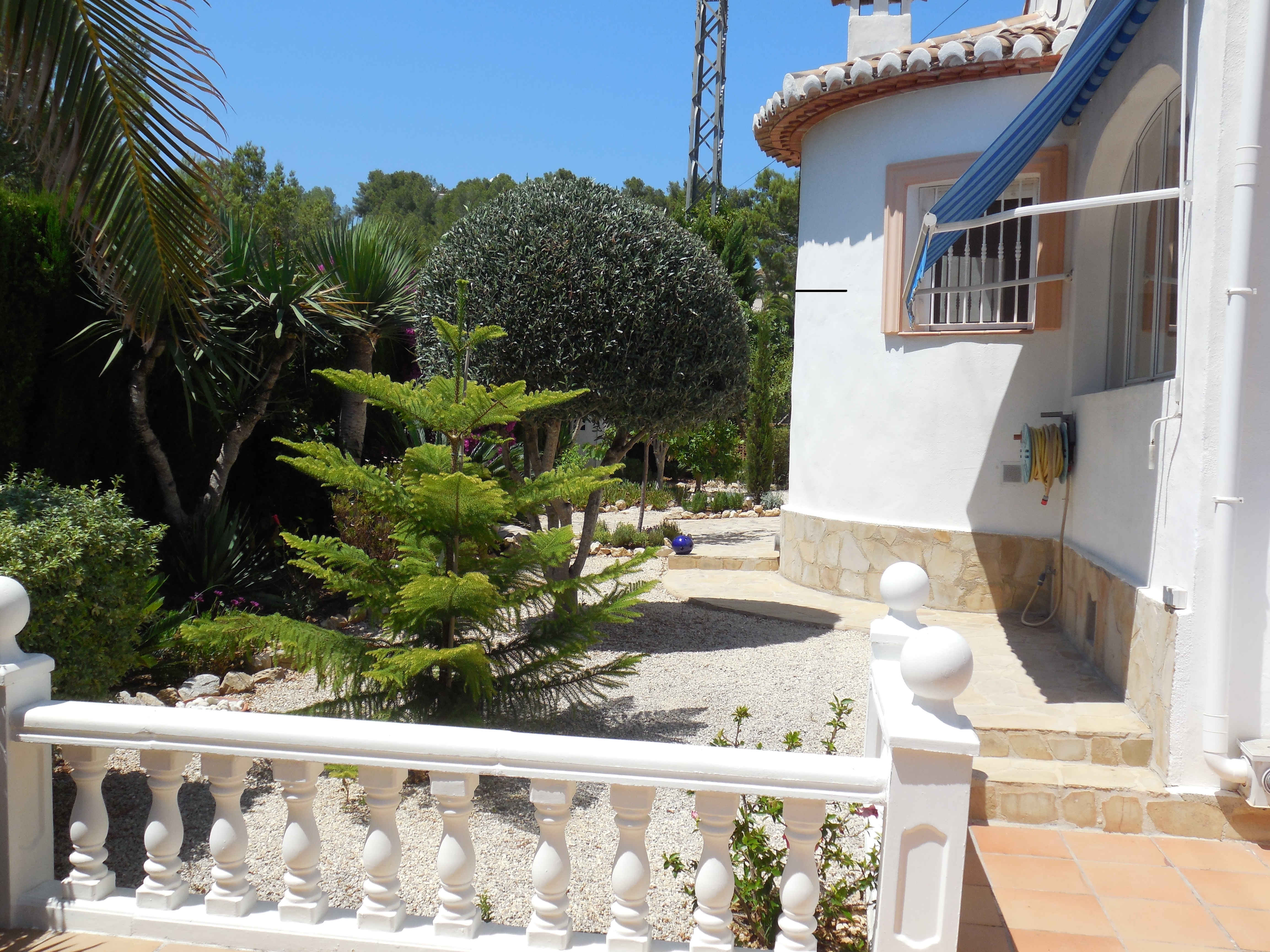 Vue du jardin avant avec gravier blanc et balustrade blanche.