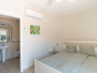 Chambre lumineuse avec salle de bain attenante, décorée d'une peinture colorée et d'un lit en bois blanc.