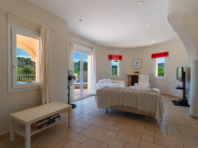 Salon lumineux avec carrelage au sol, canapé beige recouvert et vue sur l'extérieur.