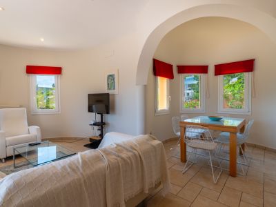 Salon-salle à manger lumineux avec carrelage, arche et rideaux rouges.